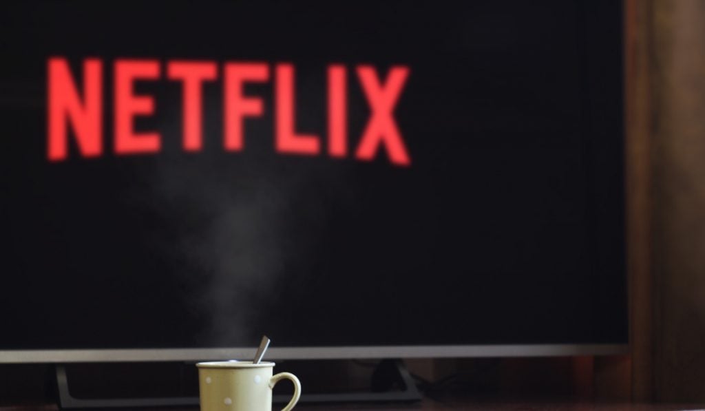 Logotipo de Netflix borroso en la pantalla de una smart tv y una taza de té en primer plano