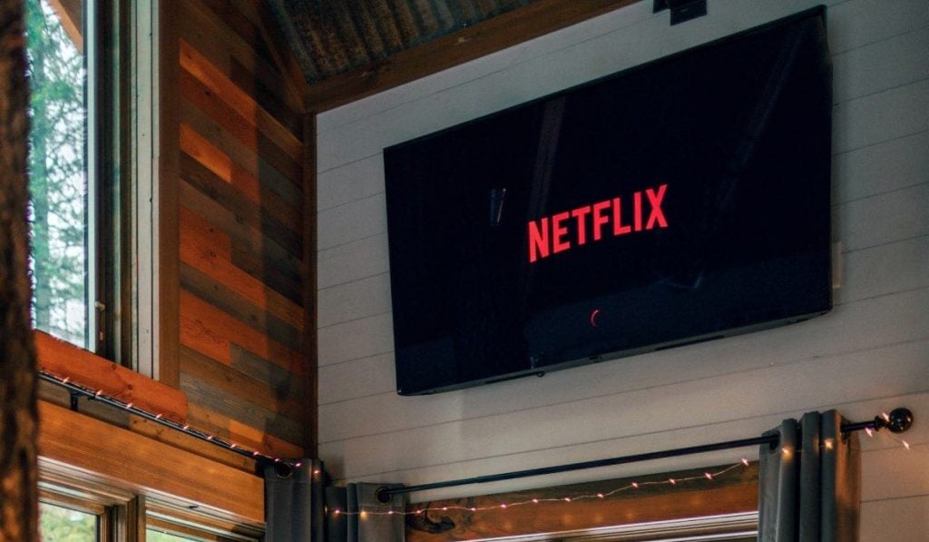 smart tv pendurada em uma parede de madeira branca ao lado de uma janela