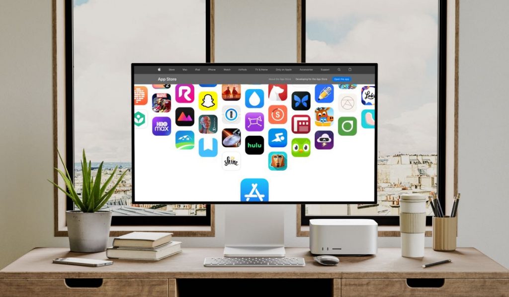 Computerscherm met App Store open omringd door planten boeken en een toetsenbord