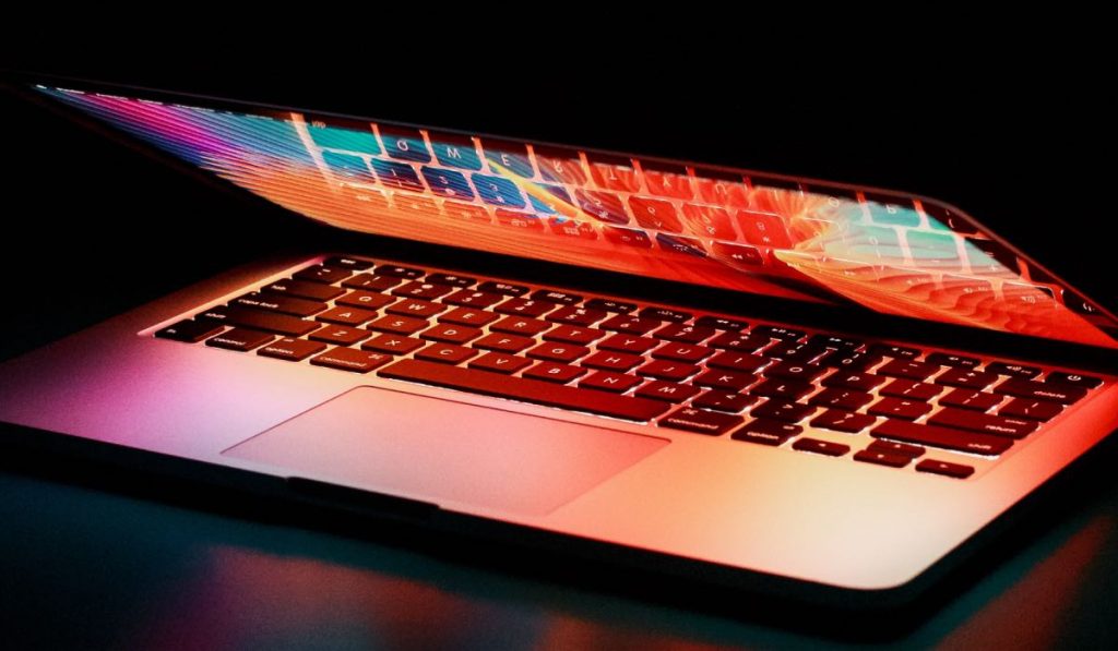 Het scherm van Macbooklaptop bijna gesloten en een toetsenbord dat in het scherm weerspiegelt
