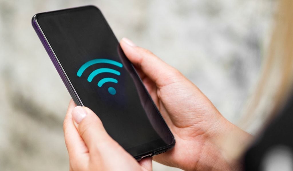 Sinal WiFi mostrado num smartphone nas mãos de uma pessoa branca