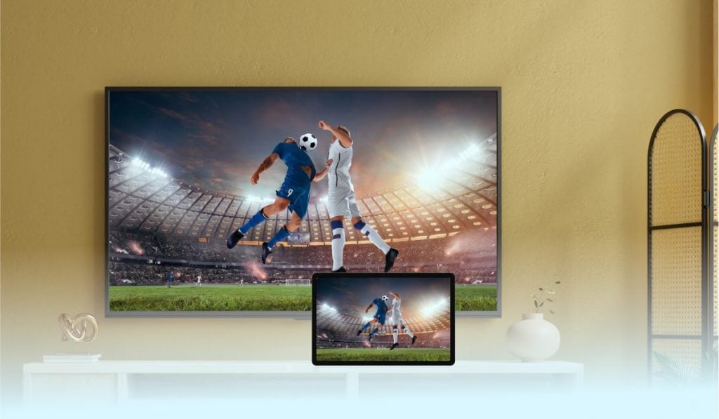 a smartphone mirroring a soccer match to a Smart TV that is standing on a short cupboard