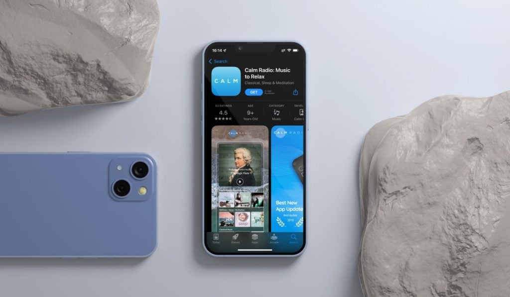 an iPhone laying on a table with the App Store open. The App Store shows the product page for Calm Radio. There are two stores - one in top-left corner, one in bottom-right corner. There is another iPhone in the bottom-left corner, laying flat on its screen