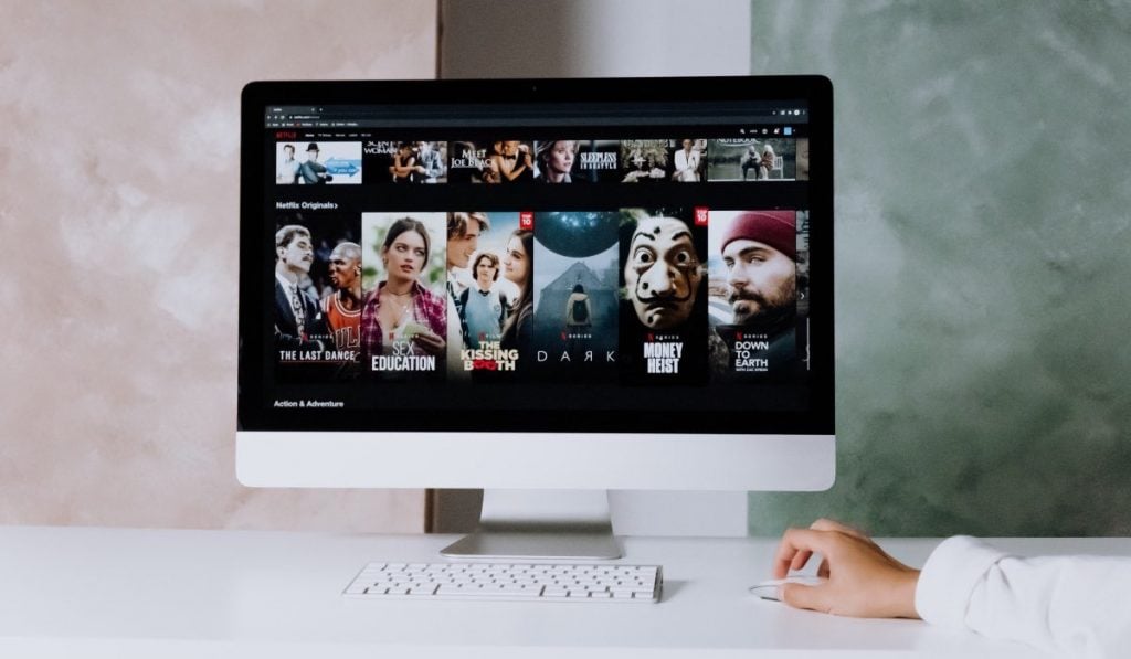 interfaccia Netflix su un monitor con una tastiera una persona che usa il mouse di un computer