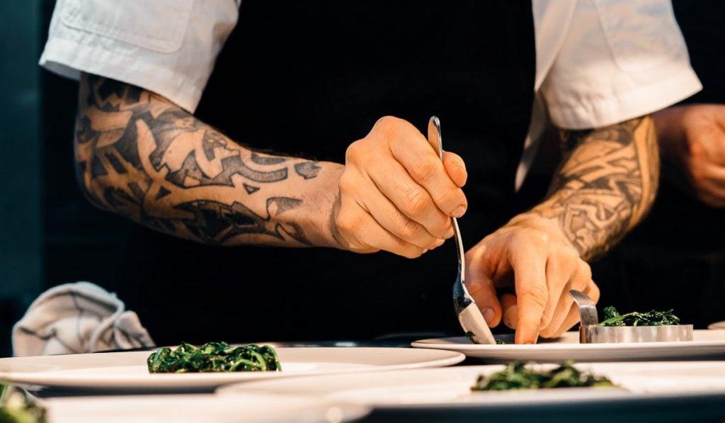 chef plating a dish with a spoon