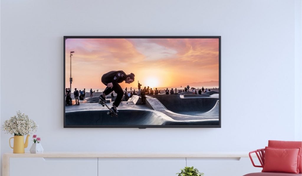an image of skaters in a skatepark displayed on a smart TV handing on a wall above some decor