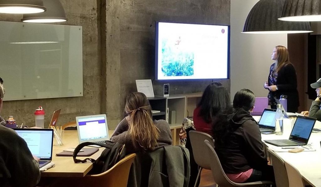 Eine Klasse von Schülern hört zu, während der Lehrer eine Präsentation auf einem Smart TV zeigt