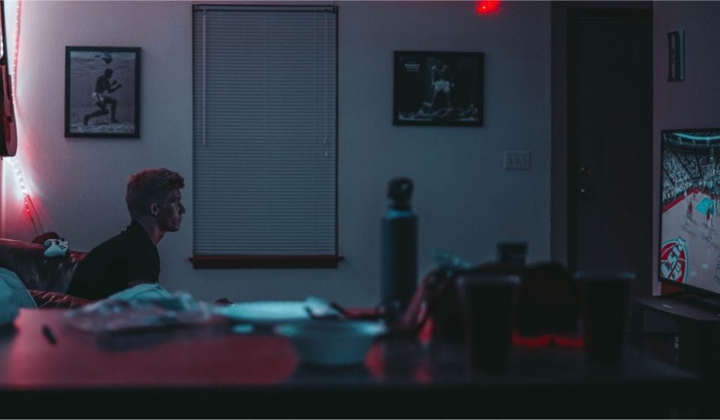 a man watching TV in a dark room