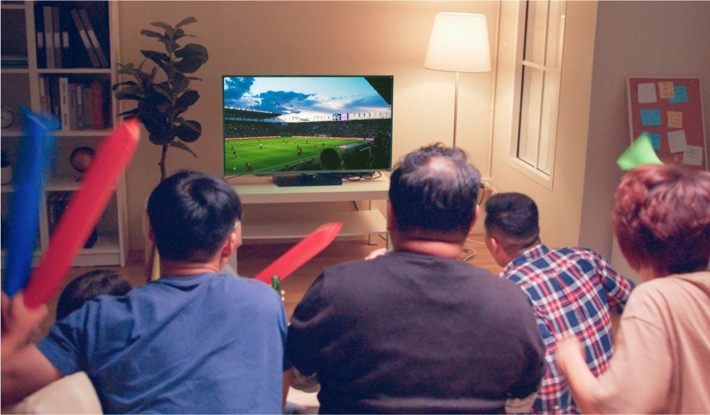 Un groupe de cinq hommes regarde le football à la télévision.
