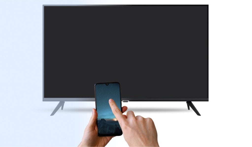 A hand with an iPhone that is pointed at a Smart Tv. The Smart TV has a black screen.