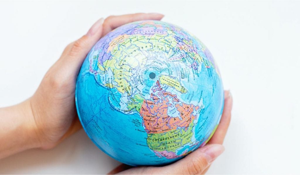 Two hands holding a small globe.