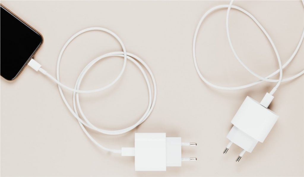 Two iPhone chargers with cables attached to them. One of the cables is plugged into an iPhone