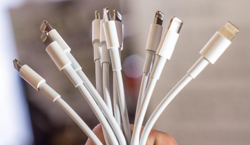 A hand holding a bundle of iPhone and USB-C charging cables