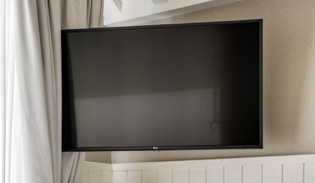An LG TV with a black screen next to a curtain.