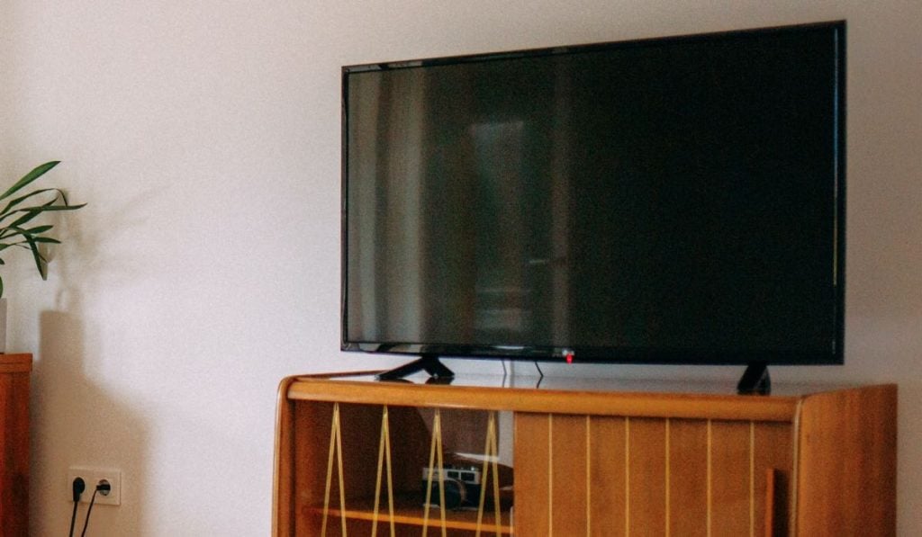An LG TV with a black screen on a wooden drawer.