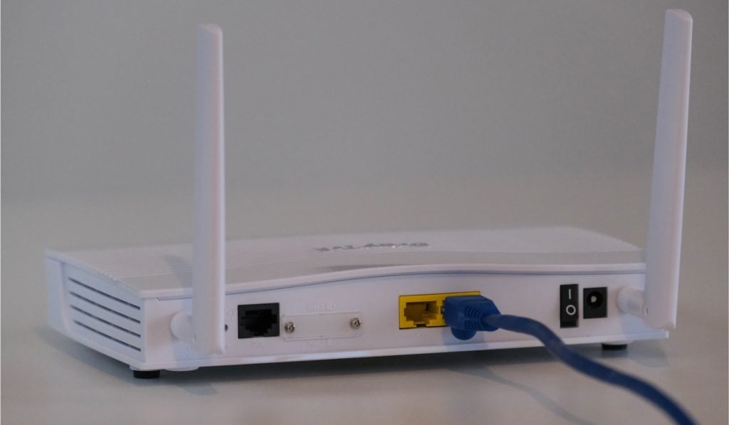 The backside of a router with a LAN cable plugged in