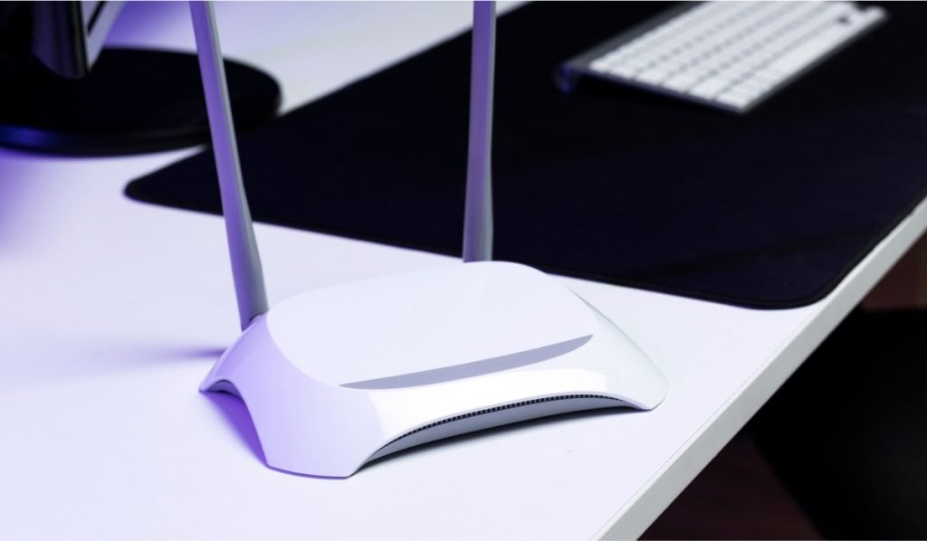 White futuristic looking router on a white table with a keyboard in the background.
