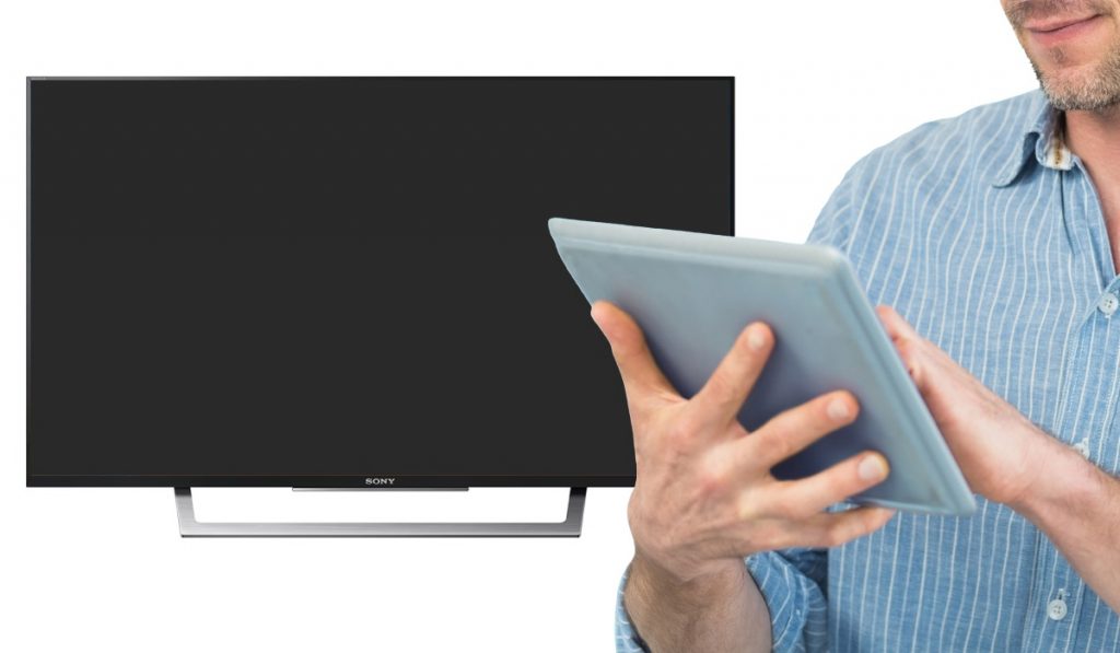A person holding a tablet and a Sony TV in the background.