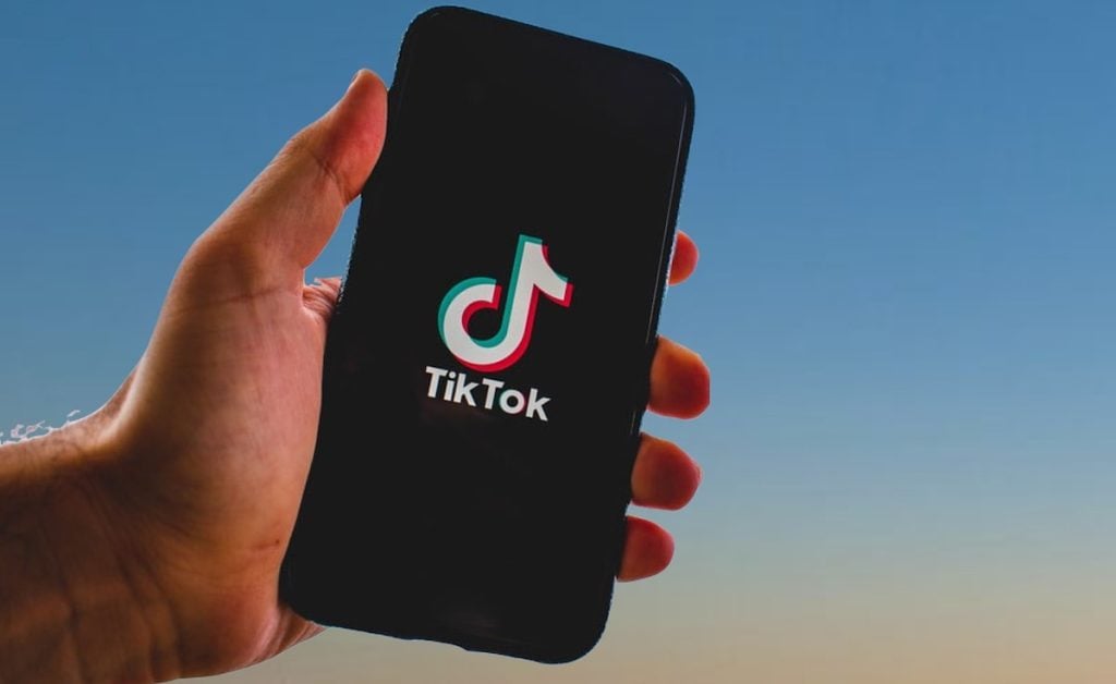 A hand holding a smartphone with a TikTok logo
