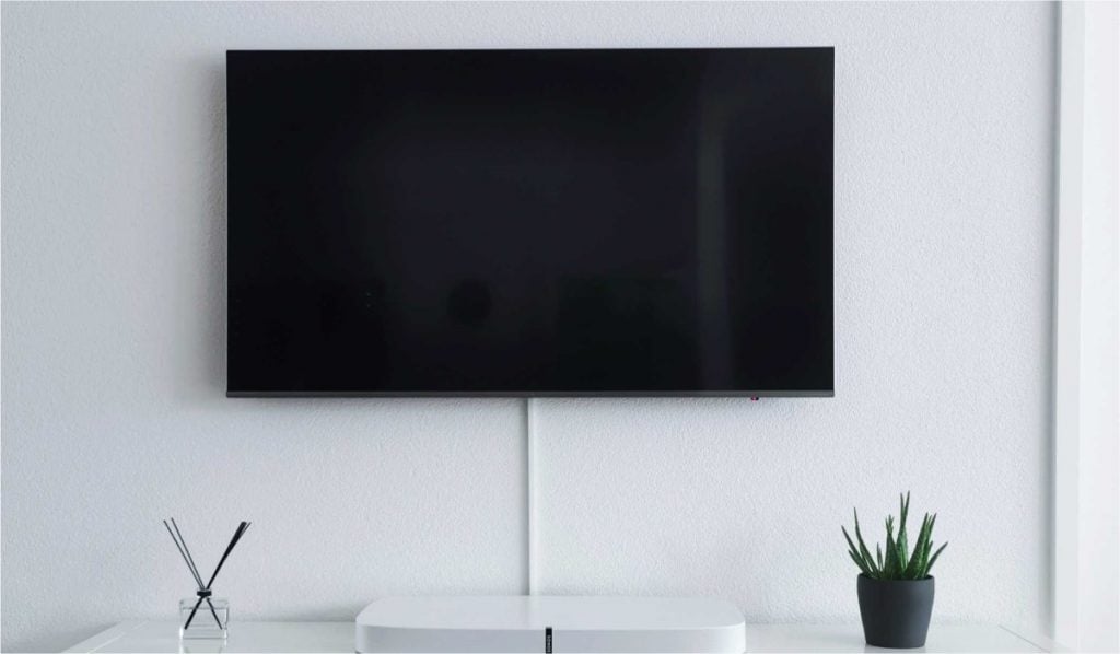 A Smart TV hanging on a wall above a soundbar and deecorations