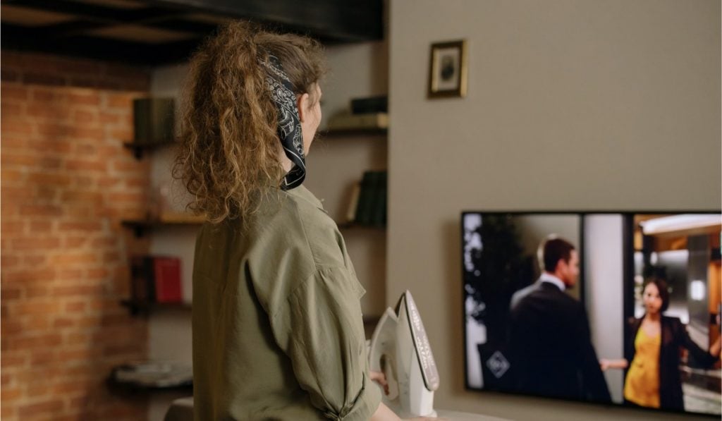 A woman in a bandana is watching TV.