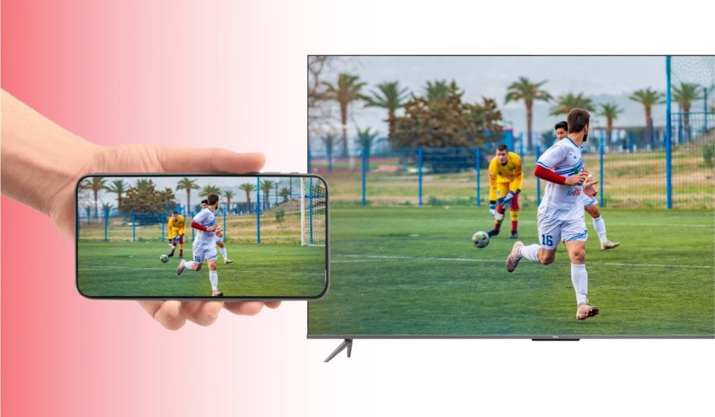 A hand holding a smartphone that is mirroring an image of a football match to a TCL tV