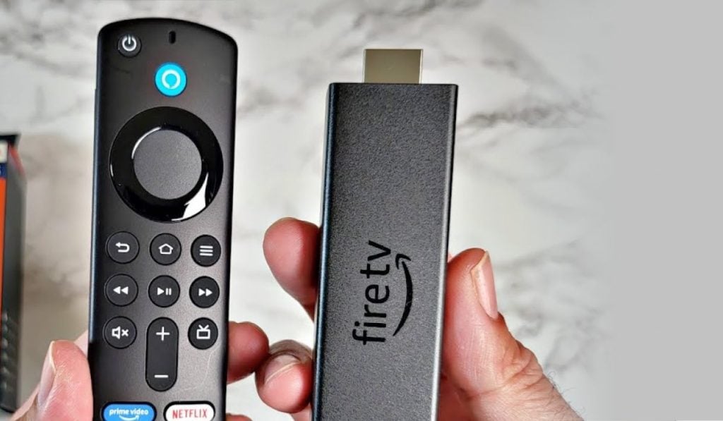 Two hands, one holding a Fire TV Stick and the other holding a Fire TV remote