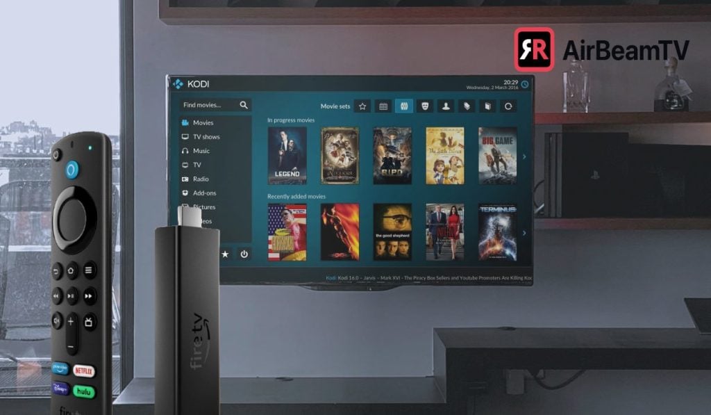 A Fire TV stick, a Fire Tv remote. A wall-mounted TV with Kodi interface on the screen