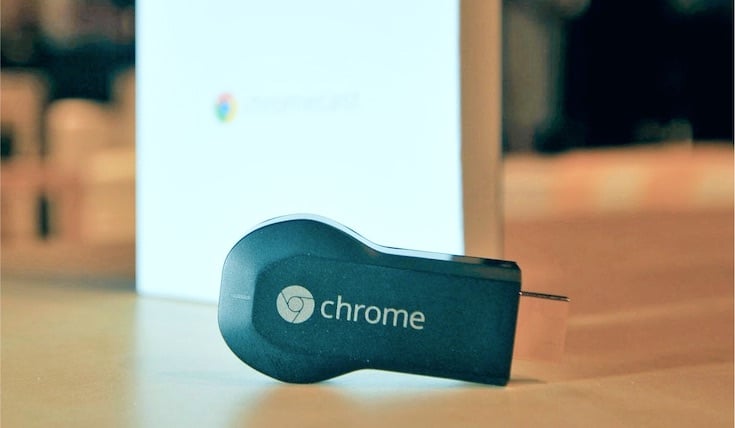 Chromecast pluggable stick and a Chromecast box on wooden surface