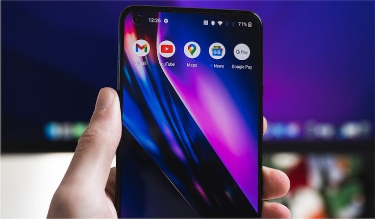 A hand holding an Android smartphone with a pink-black wallpaper and five app icons