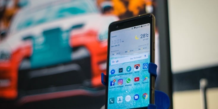 Samsung smartphone with weather app on the screen. A TV in the background