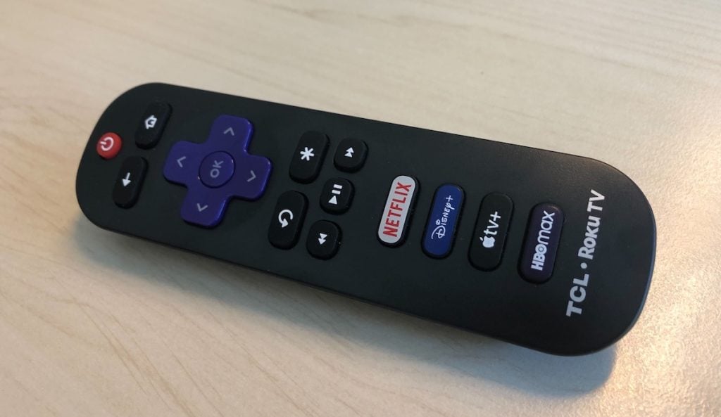 A TCL Roku TV remote control on wooden surface