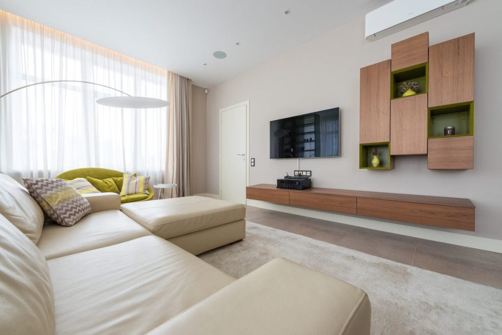 A modern living room with beige furniture. There is a wall-mounted TV