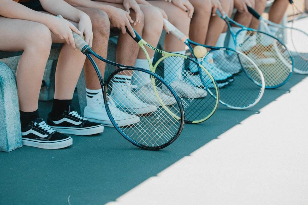 Tennis players with rackets in hands sitting down.