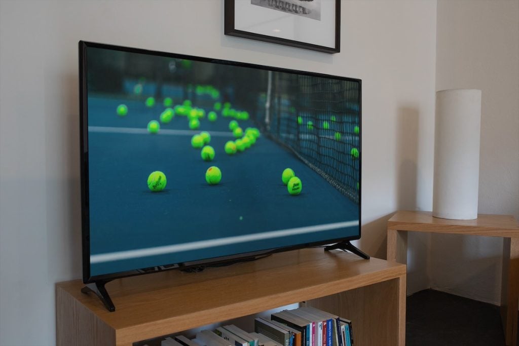 Image of tennis balls on tennis court on a TV screen