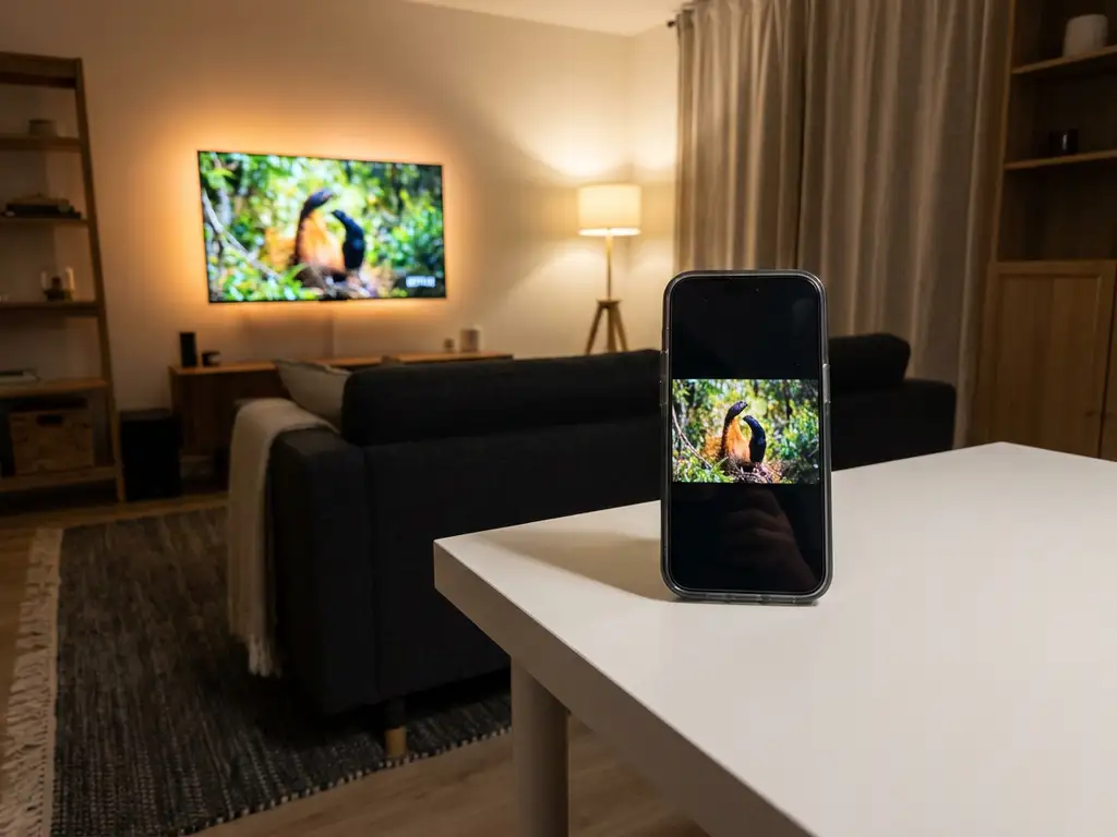 iPhone wirelessly mirroring its screen to an Amazon Fire TV in a modern living room with warm ambient lighting.